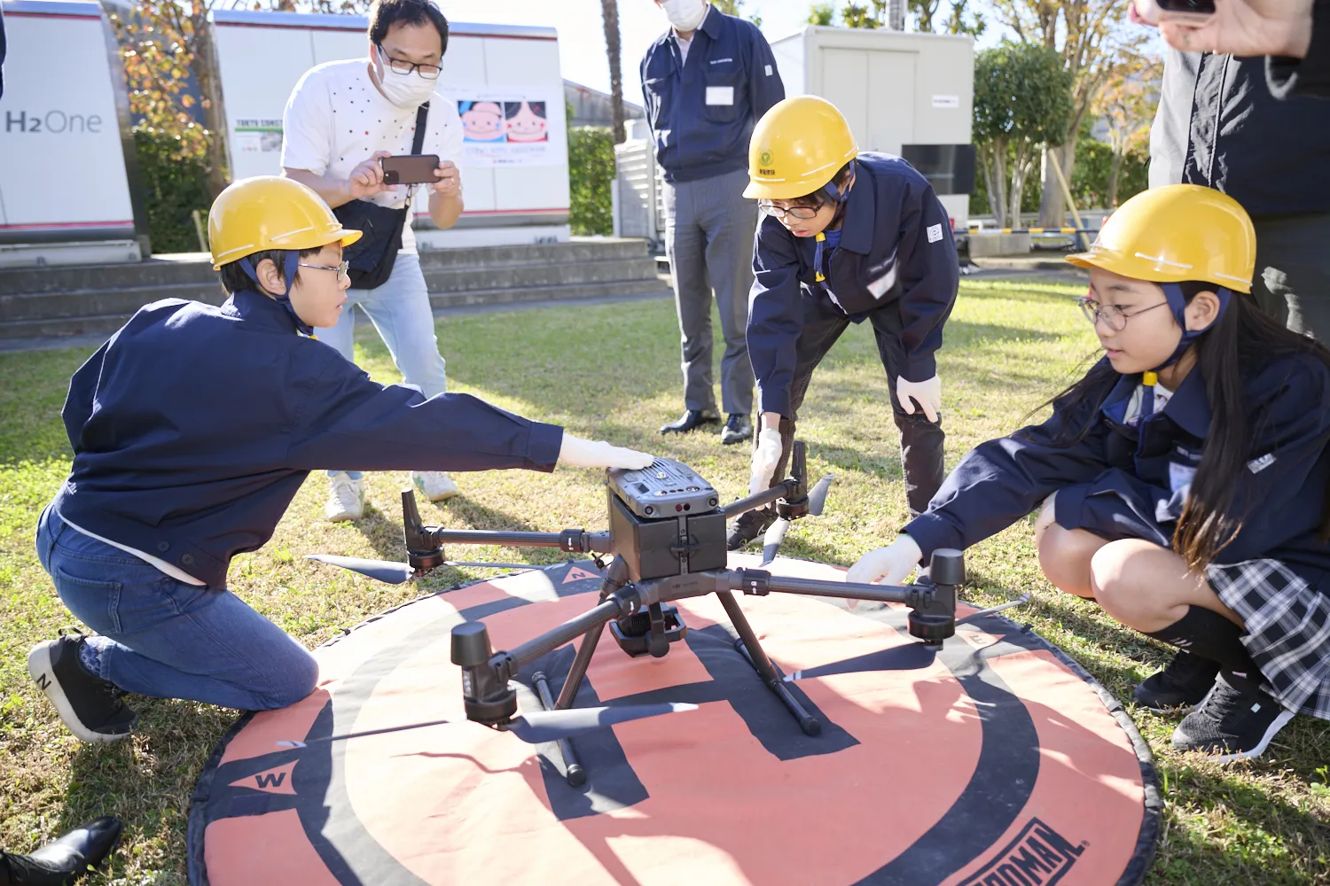 建設現場で使われる業務用ドローンについて教わる子どもたち